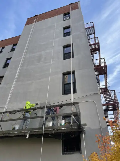 Stucco work on an apartment building wall from a scaffold platform
